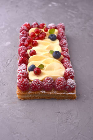 Delicious raspberry and blueberry tart with whipped cream on a concrete backgroundの写真素材