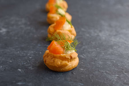 Canape with salmon, cream cheese and dill on dark background