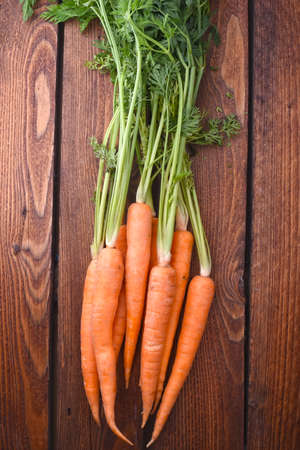 Bunch of fresh carrots on the wooden backgroundの写真素材