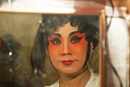 Chinese opera actress is painting mask on her face before the performanceのeditorial素材