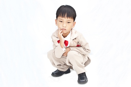 Little boy with brown tuxedo and red bow tie on white backgroundの写真素材
