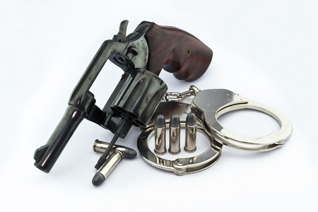 handgun revolver and police handcuff with bullets on white backgroundの写真素材