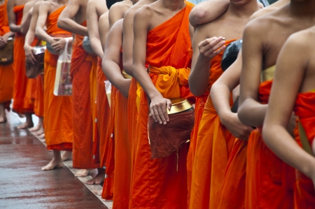 NAN,THAILAND-MAY 26:A long line of monks receiving rice offering from people at Nan City in Nan Province,Thailand on October 26 2012. Offering food is the oldest of Wesak Day in Buddhism 2600 year.のeditorial素材