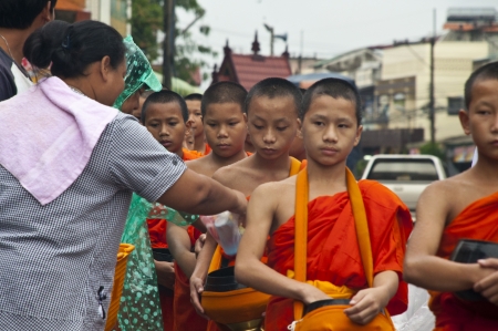 NAN,THAILAND-MAY 26:A long line of monks receiving rice offering from people at Nan City in Nan Province,Thailand on October 26 2012. Offering food is the oldest of Wesak Day in Buddhism 2600 year.のeditorial素材