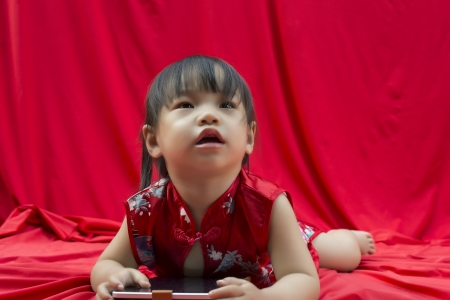 China girl in traditional Chinese red Tang suit greeting and play smartphoneの写真素材