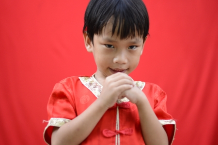 China boy in traditional Chinese red Tang suit greeting and play smartphoneの写真素材