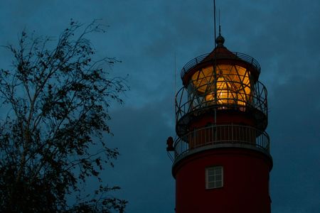 The beacon shines yellow light against the dark blue skyの写真素材