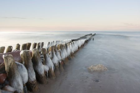 The iced over breakwater on a decline, washed by northern seaの写真素材