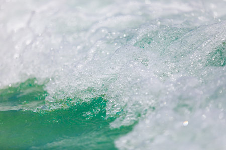 Powerful, stormy, foamy waves are picked up by the wind. White foam from bubbles of different sizes is scattered to the sides. Close-up.の写真素材