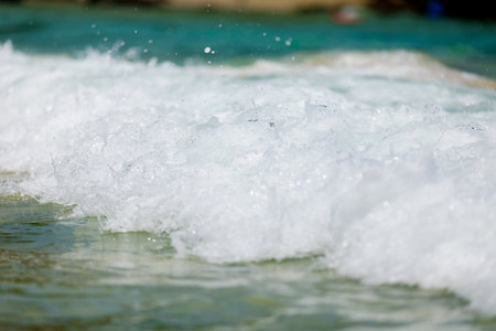 Powerful, stormy, foamy waves are picked up by the wind. White foam from bubbles of different sizes is scattered to the sides. Close-up.の写真素材