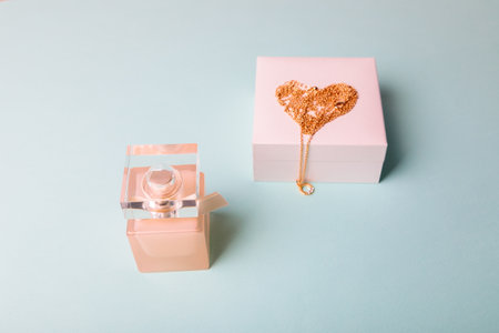 A gift for Valentines Day. Perfume and a box with a gold chain on a blue background. Chain in the shape of a heart.の写真素材