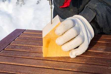 The man uses a cordless screwdriver to drive a screw into the block. Connects a cube and a triangle.の写真素材