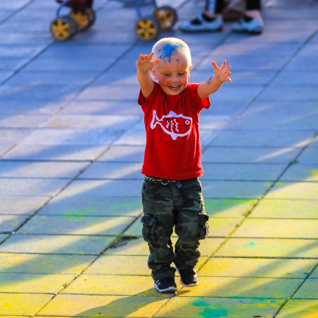 Russia, Moscow - June 25, 2017. Little boy with bright colors on his face. Laughs with happiness. Holi is a traditional holiday in Indiaのeditorial素材