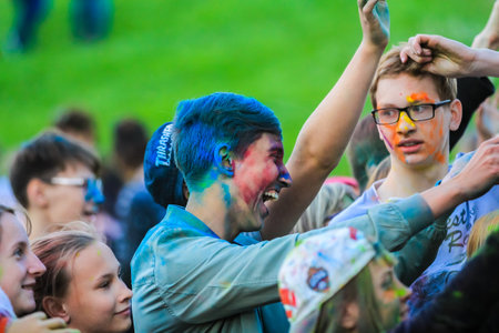 Russia, Moscow - June 25, 2017. Portrait of a young man with bright colors on his face. Laughs with happiness. Holi is a traditional holiday in Indiaのeditorial素材