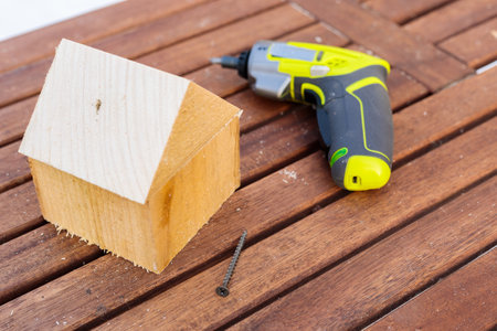 On the table is a modern miniature working tool for screwdriving screws. Craft from wooden bars.の写真素材