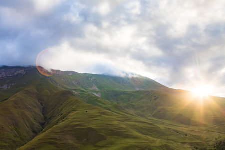 Early morning in the mountains, the first rays of the sun come out over the peaks of the ridge. Magnificent mesmerizing landscape.の販売画像