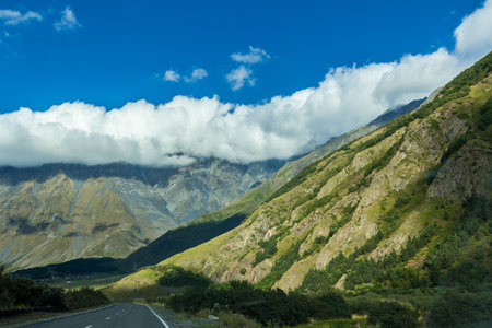 Landscape of the green mountains of the Caucasus thick clouds cover the peaks of the ridge. The outgoing road to the valley.の写真素材