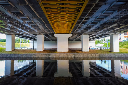 Powerful iron bridge structure, View from below. Concrete pillars, big iron rivets. A river flows under the bridge. Perspective.の写真素材
