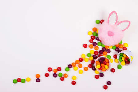 Easter concept, candy pills, egg, pink bunny head toy on white background. Place for text