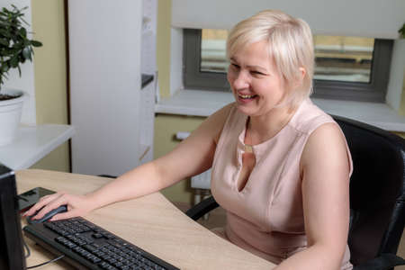 A female director working in an office is sitting at a table, analyzing business statistics,...