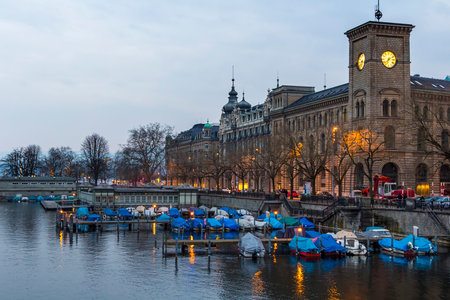 Switzerland, Zurich March 23, 2013 City evening landscape with illumination. Covered boats at the pier, reflected in the water.のeditorial素材