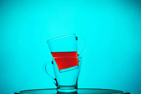 Glass mugs with tea, one inside the other, still life on a blue background. Close-upの写真素材