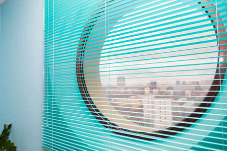 Office interior with round window closed by blue blindsの写真素材
