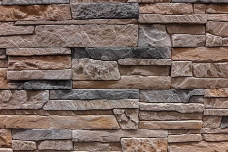 The wall is made of multi-layered natural stone. Stone for building a house.