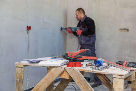 An electrician drills holes for sockets with a diamond core bit