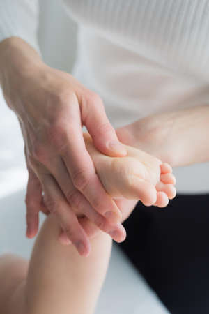 Mom gives her baby a leg and foot massage. Close-up.の写真素材