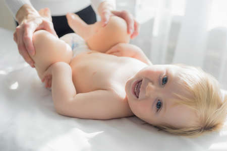 Mom does baby gymnastics for the babys legs. Close-up.の写真素材