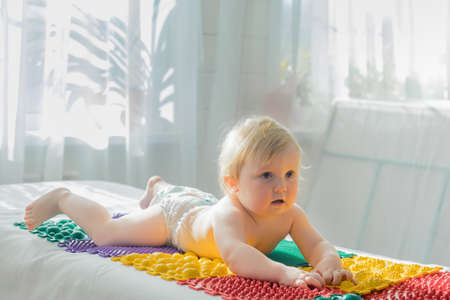 The baby lies on the massage mats with his stomach down.