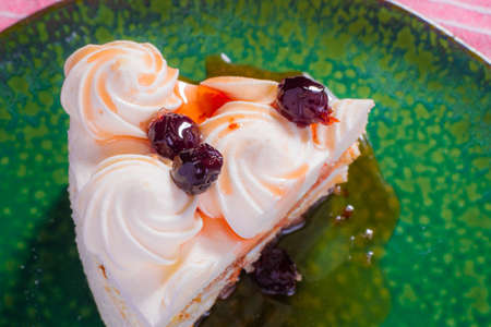 Slice of sponge cake with white cream and red cherry syrup.の写真素材