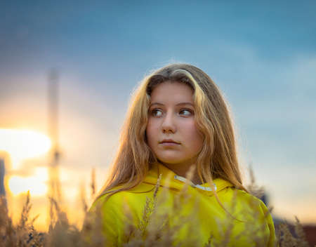 A young girl with long hair walks across a field with tall grass. Blonde hair.の写真素材