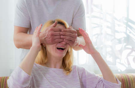 The family makes a surprise for mom, wishes her a happy holiday. Dad covered his mother's eyes with his palms.の写真素材