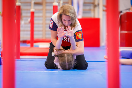 Gymnastics coach stretches a young athlete in the gym. Moscow, Russia September 18, 2019のeditorial素材