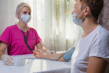 A girl doctor measures the blood pressure of an adult woman.