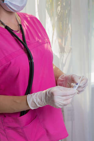 A girl doctor in a mask and gloves checks the temperature on a thermometer.の写真素材