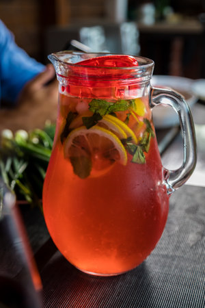 Lunch with a decanter of chilled red fruit drink with lemon and mint wedges. Close-up.の写真素材