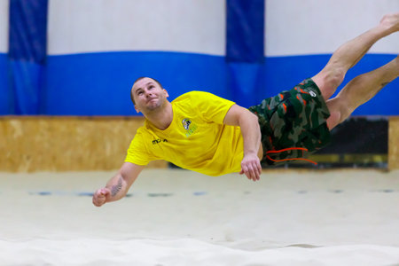 A man jumps for a volleyball on the sand.