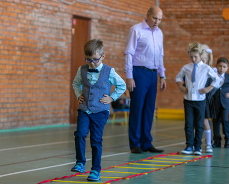 First graders in their first physical education class at the gym. The teacher assigns a task to the students. Moscow, Russia, September 2, 2019のeditorial素材