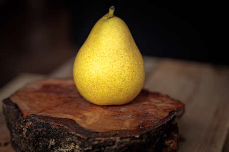 Juicy yellow pear on a wooden background from old boards in a low key. Ripe pear for a healthy diet.の写真素材
