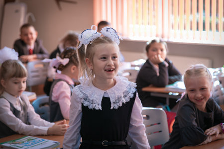 The first grader stands at the desk and answers the teachers question.