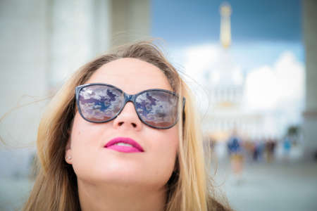 Cute girl in sunglasses. The clouds are reflected in the glasses. Happy girl face close up.の写真素材