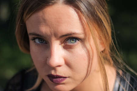 Close up portrait of a serious young girl. The girl looks into the camera with a piercing gaze