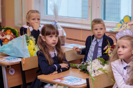 On September 1, children sit at their desks in class. First graders listen carefully to the teacher in the first lesson. Moscow, Russia, September 2021のeditorial素材