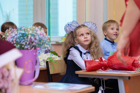 On September 1, children sit at their desks in class. First graders listen carefully to the teacher in the first lesson. Moscow, Russia, September 2021のeditorial素材