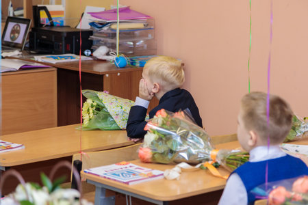 On September 1, children sit at their desks in class. First graders listen carefully to the teacher...