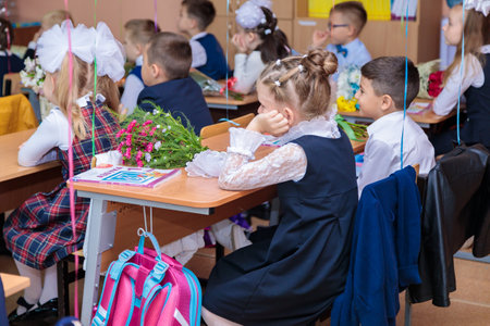 On September 1, children sit at their desks in class. First graders listen carefully to the teacher in the first lesson. Moscow, Russia, September 2021のeditorial素材