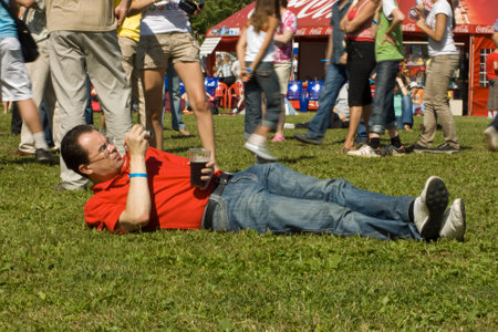 A man lies on the lawn with a glass of beer and photographs people. Celebration, festival. Moscow, Russia, June 25, 2009のeditorial素材